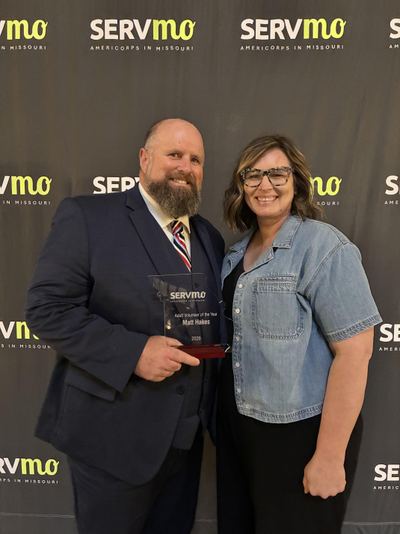 Matt and Heidee Hakes at an awards ceremony; Matt holds a Volunteer of the Year award