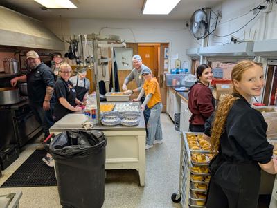 Many Parts, One Body volunteers plating trays of food together in a community kitchen